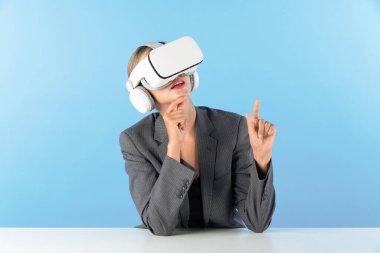 Profesyonel iş kadını VR gözlüğü kullanırken veri analizini karşılaştırıyor. Beyaz yönetici görsel gerçeklik kulaklığı kullanarak metaevrene bağlanırken finansal verilere bakıyor. Kısıtlanma.