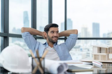 Modern ofis binasında otururken rahatlamış genç mimar mühendisinin tasarım ve dinlenme portresi. Erkek işçi ya da yönetici ara verir, bitirme projesinin ardından el ele tutuşur. İzleme