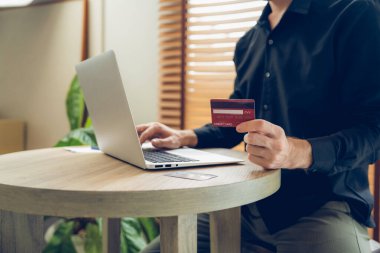 Genç adam internet bankacılığı için kredi kartlı dizüstü bilgisayar kullanıyor. İnternet üzerinden alışveriş yapıyor. Banka kartıyla modern ve kullanışlı online satın alma. Açılıyor