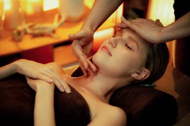 Beyaz kadın stres önleyici kafa masajı yapmaktan ve lüks otel veya otelde sıcak mum ışığında yüz güzelliği eğlencesi yapmaktan zevk alıyor. Sessiz.