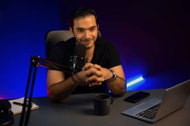 Yayıncı, fanclub dinleyicisiyle mikrofon kullanarak konuşuyor. Mor neon ışıklı modern stüdyoda yaratıcı olumlu düşünce konseptiyle canlı yayında finansal sorunları tartışıyor. Tahmin et..