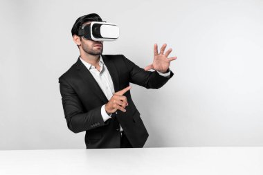 Akıllı yönetici veri analizine işaret ederken VR gözlüğü kullanarak veriye bakıyor. Beyaz yatırımcı takım elbise ve sanal gerçeklik kulaklığı takarken metaevreni birbirine bağlıyor. Yenilik teknolojisi. Sapma.