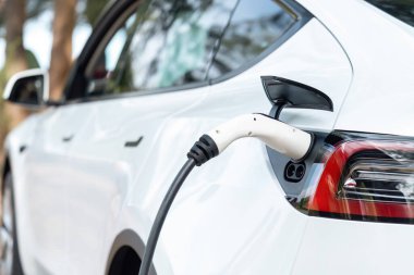 Kapalı EV şarj kolu fişe takıldı veya elektrikli arabaya bağlandı, EV araba aküsünü temiz çevre için sıfır CO2 emisyonu ile alternatif ve sürdürülebilir enerjiyle şarj etti. Kalıcı