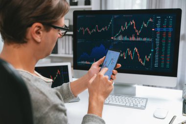 Akıllı borsa yatırımcıları ekranda akıllı telefon ile piyasa borsasını işaret ederek dizüstü bilgisayarın yanı sıra en yüksek dinamik yatırım oranını göstererek, modern işyerindeki veri planlamasına odaklanıyorlar. Bireysel.