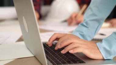 Mimarlık ve güvenlik mühendisi, modern ofiste dizüstü bilgisayarda mimari belge ve ahşap blokla sergilenen planlar hakkında tartıştı. - Yakın çekim. Tanımlama.