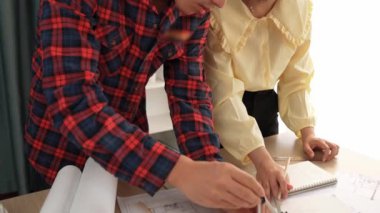 Mimarlık ve güvenlik mühendisi, modern ofiste doğruluk için mimari belge ve ölçüm aracı kullanılarak dizüstü bilgisayarın üzerinde sergilenen planlar hakkında tartıştı. - Yakın çekim. Tanımlama.