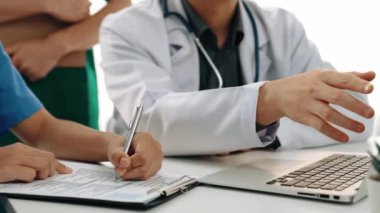 Hasta için hastane masasında çalışan ve tıbbi tedavi planlayanlardan oluşan profesyonel bir ekip. Takım çalışması başarılı hastalıklara ve hastalıklara yol açar. Ağır çekim. Katı.