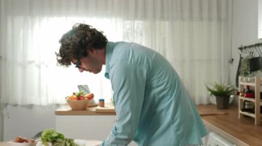 Mutlu baba yemek pişirirken müziğe geçiyor ve modern mutfakta öğle yemeği hazırlıyor. Aktif baba, sebze ve mutfak gereçleri ile çevrili sağlıklı yemek ya da salata yaparken şarkıyla dans ediyor. Pedagoji.