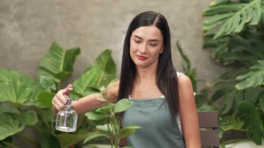 Genç kadın bahçıvan, minimalist mimari beton tarzında tropikal bitkilerle ilgileniyor ve onları suluyor. Yaz mevsiminde egzotik bitki yetiştirme bahçeleri, çevreci yaşam tarzları için bahçeler. Blithe