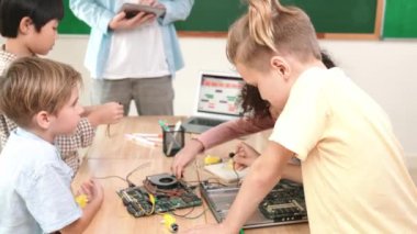 Öğretmenler tablet verileri analiz ederken sevimli enerjik çocuklar elektronik panoda çalışıyor. Çeşitli öğrenci grubu ana tahtayı tamir ediyor ve yapay zeka ve programlama sistemini öğreniyor. Pedagoji.
