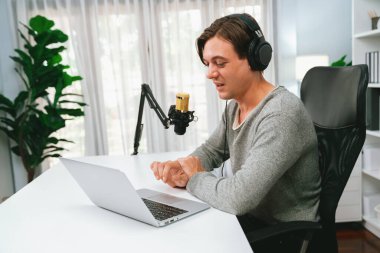 Sunucu kanalı, gülümseyen akıllı yayıncı kaydı, senaryosu ve akıllı telefonuyla sosyal medyada sohbet programı, kulaklık takarak modern ev stüdyosundaki video flamalarını kaydediyor. Bireysel.