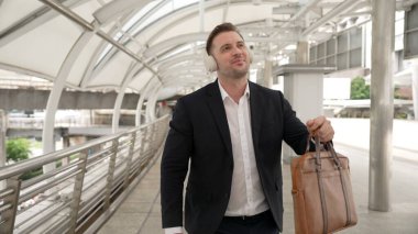 Şehir merkezinde Briç oynarken kulaklık takan mutlu bir iş adamı. Enerji yöneticisi neşeli ve motive edici performans yürürken başarılı projeyi kutlamak için müziğe geçiyor. Urbane.