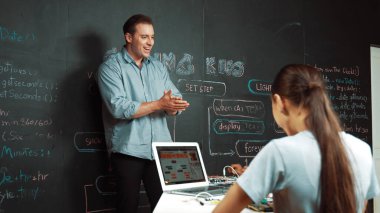 Kafkas öğretmeni alkışlayarak öğrencileri kodlamayı veya programlamayı teşvik etmek için alkışlıyor. Çeşitli öğrenciler STEM sınıfına katılırken başarılı bir projeyi kutlamak için el çırpıyorlar. Öğretim.