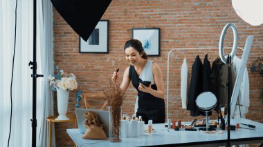 Kadın nüfuzlu kişi canlı yayın yapan video görüntülerini sosyal medya ya da blog üzerinden gözden geçiriyor. Kozmetik stüdyosu ışıklandırmalı mutlu genç kız çevrimiçi pazarlama oturumu yayını için..