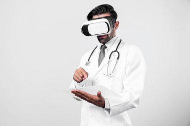 Doktor beyaz arka planda tıbbi tabloya bakarken sanal gerçeklik gözlüğü takıyor. Laboratuvar önlüklü profesyonel doktor başvuru formunu tutarken VR gözlüğü kullanıyor. Sapma.
