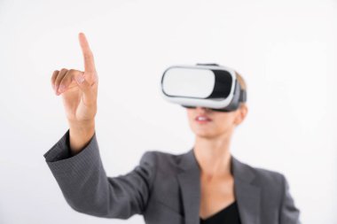 Profesyonel kadın lider programa dokunuyor ya da sanal gerçeklik gözlüğü kullanırken çalışıyor. Yetenekli iş kadını, görsel gerçeklik gözlüğü takarak metaevrene bağlanırken sistemi işaret ediyor. Kısıtlanma.