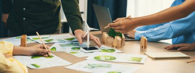 Yenilenebilir enerji ve eko kenti temsil eden ahşap bloğu temsil eden yel değirmeni modeli, çevreci dökümanların dağıtıldığı yeşil iş toplantısı masasına yerleştirildi. Ön manzara. Tanımlama.