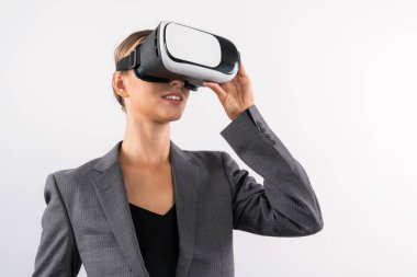 Yetenekli bir iş kadını arka planda dururken VR cam kullanarak görsel gerçeklik dünyasına bakıyor. Teknoloji yeniliklerini kullanarak metaevreni bağlamak için VR gözlüğü tutan akıllı bir yönetici. Kısıtlanma.