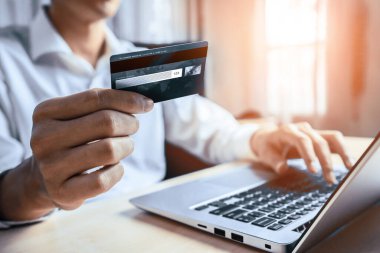 Genç adam, laptop bilgisayar başvurusu ya da web sitesinde online alışveriş yapmak için kredi kartı kullanıyor. E-ticaret ve online alışveriş konsepti. uds