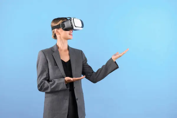 stock image Businesswoman with VR glasses standing and present idea with confident while standing at blue background. Professional project manager wearing suit while holding something. Technology. Contraption.