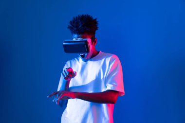 Sanal gerçeklik dünyasını dijital fütüristik teknolojiye bağlayan mavi pembe ışık duvarını gösteren 3 boyutlu hologram gösteren genç bir Afro-Amerikan oyun oyuncusu. Entrika.