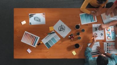 Proje yöneticisi renk paletleri seçerken tasarımcının tablete baktığı yukarıdan aşağıya hava görüntüsü. Profesyonel grafik tasarımının en üst görüntüsü ve logoya bakın. Yetenekli ekip grafikleri seçiyor. Sempozyum.