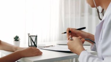 Hasta klinikte ya da hastane ofisinde doktor randevusuna gidiyor. Hastaların risk faktörünü tespit etmek için nabzını ölçmek için steteskopla doktor muayenesi ve teşhis semptomları. Ağır çekim. Katı.