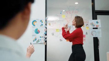 Yetenekli genç ve güzel iş kadını, yaratıcı iş toplantısında yakışıklı yönetici dinlerken zihin haritalama ve istatistiksel grafik kullanarak pazarlama fikrini kendine güvenle sunuyor. Tertemiz..