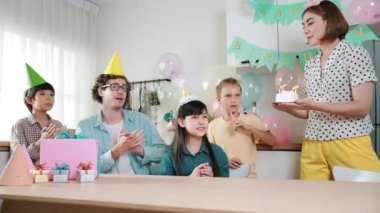 Asyalı kız dilek tutarken ve doğum günü mumu üflerken pasta yiyor. Kafkasyalı anne pasta tutuyor ve enerjik çocuk mum üflerken kızına yerleştiriyor. Güzel bir aile el çırpıyor. Pedagoji.