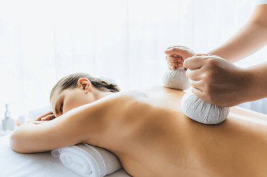 Sıcak bitkisel top spa masaj vücut tedavisi, masör kadın vücuduna nazikçe şifalı bitki torbası bastırıyor. Aromaterapi dinlenme sükuneti ve sükuneti kaplıca salonundaki atmosferi aydınlatıyor. Sessiz.