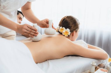 Sıcak bitkisel top spa masaj vücut tedavisi, masör nazikçe bitki torbasını çift müşteri vücuduna bastırıyor. Aromaterapi dinlenme sükuneti ve sükuneti kaplıca salonundaki atmosferi aydınlatıyor. Sessiz.
