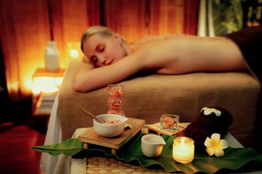 Lüks spa salonlarında sıcak mum ışığında cilt bakımı yaptıran kadın müşteri. Sağlık Spa vücut fırçasında tuz temizleme güzellik tedavisi. Sessiz.
