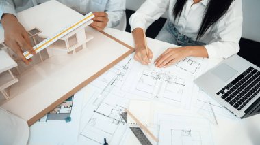 Profesyonel mühendis ev modelini tartartarken, yetenekli tasarımcı da planına yazar. Birlikte çalışmak, işbirliği, işbirliği. Yaratıcı tasarım ve takım çalışması konsepti. - Yakın çekim. Tertemiz.