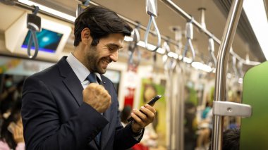 Profesyonel iş adamı trende dururken terfi aldığı için kutlama yapıyor. Beyaz erkek, telefona bakan lider başarılı proje hakkında iyi haberler alırken satışları artırıyor. Sevinçli..