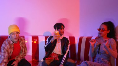 Takım çalışmalarını kutlamak için neon lambalı çok kültürlü bir arkadaş bardak tokuşturuyor. Renkli meyve suyu ve tokuşturarak şık modaya sahip profesyonel çeşitli insanlar. Mutluluk.