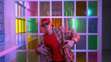 Komik break dansçı kameraya bakarken hiphop 'a doğru serbest adım atıyor. Çılgın mutlu hipster dans edip sokak dansı yaparken Led ışığında günlük kıyafet ve güneş gözlüğü takıyor. Mutluluk.