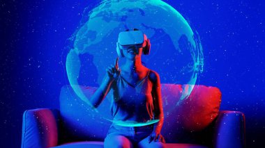 VR kullanarak kanepedeki kadını oturtmak yüzeyi döndürerek metaevreni döndürerek parlak ışıklı neon evren sanal uzay fantastik keşif bulutsusu 3D meta küresel hologram. Halüsinasyon.