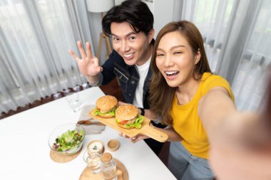 Gülümseyen ev sahibi aşçıların akıllı telefonuyla fotoğraf çekerken üst görüntüsü yemek programında çift hamburger tutarken sosyal medya kanalında ev yapımı salata tabağıyla kolaylıkla görülebiliyor. İnfobahn.