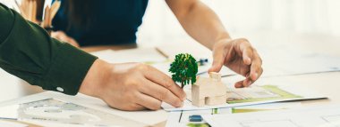 Profesyonel mimar takımı, Echo House 'un yeşil tasarımı hakkında toplantı masasının üzerinde plan ve model dağılımı ile tartışır. - Yakın çekim. Eline odaklan. Yeşil şehir konsepti. Tanımlama.