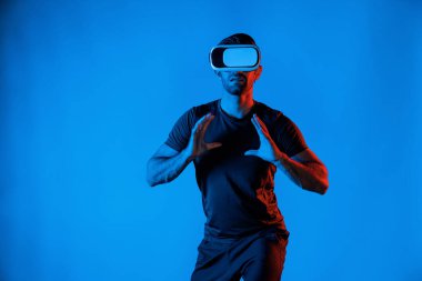 Kafkasyalı bir adam metaevrene girmek için VR kulaklık takarken basketbol oynuyor ya da neon ışıklı bir dünya canlandırıyor. Sanal gerçeklik dünyasında dururken spor yapan ya da egzersiz yapan sporcu. Sapma.