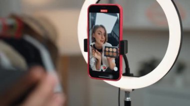 Arka plan etkileyicisi, vlog video gözden geçirme makyaj primi sosyal medya ya da blog kullanarak akıllı telefon yayınıyla canlı çekim yapıyor. İnternetteki pazarlama kaydı için kozmetik stüdyosu ışıklandırması olan kız.