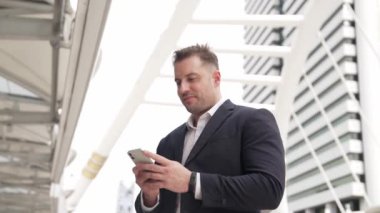 Kafkasyalı iş adamı şehir merkezinde dururken cep telefonlarını kontrol ediyor ve pazarlama ekibinden satış raporlarını inceliyor. Yetenekli bir yönetici cep telefonu üzerinde çalışıyor ve veri analizine bakıyor. Urbane.