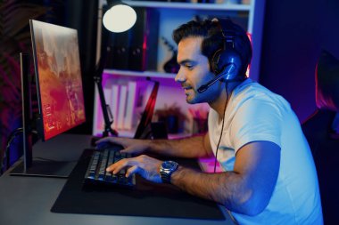 Akıllı oyun flaması dijital neon ışıklı siber odada kulaklık takarak bilgisayar ekranında çoklu ya da tek oyuncuyla çevrimiçi atış oyunu oynayan bir savaş takımı ile oynamaktan zevk alır. Tahmin et..