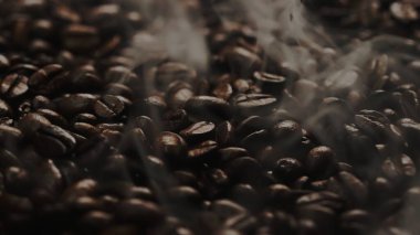 Kahve çekirdeği yığınından çıkan kavrulmuş dumanla taze kahve çekirdeğini kapat. Kokulu ve kokulu sıcak dumanlı sıcak kahve çekirdeğinin makrografisi fasulye yığınından gelir. Yukarıdan aşağıya doğru. Geliştirilebilir.