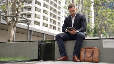 Kafkas iş adamları yeşil şehirde otururken tablet üzerinde çalışıyorlar. Uzman yönetici iş ekibiyle çalışırken finansal veri analizi yapmak ve aramak için tablet kullanıyor. Urbane.