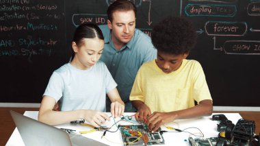 Zeki akıl hocası ana tahtanın yapımını öğretirken farklı gençlerin öğrenme sistemleri var. Öğretmen, akademik öğrenci elektronik ekipman kullanmayı öğrenirken anakart yapısını açıklıyor. Öğretim.