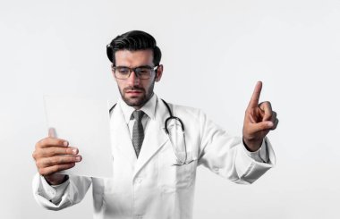 Beyaz arka plana bakıp laboratuvar önlüğü giyerken parmak gösteren beyaz bir doktor. Sağlık verilerini gösterip saklarken tıbbi teknolojiyi kullanan uzman bir doktor. Sapma.