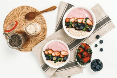 Meyvelerin sunduğu yoğurt malzemelerini çilek, yulaf, kuru üzüm ve nane şekeriyle süslenmiş Chia tohumu ile beyaza boyarız. Pembe arka plan. Sağlıklı süt ürünleri seti. Bireysel.