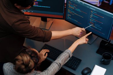 Akıllı web sitesi geliştirme kodlayıcı sistemi ile tartışan IT geliştiricilerinin üst görüşü modern ofisteki neon ışık odasında iki ekran bilgi teknolojisini çevrimiçi çalıştırıyor. İnfobahn.