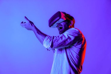 VR cam takan ve hareket eden el kol tabancası tutan bir adamın yan görüntüsü. Oyuncu, gelecekteki sanal gerçeklik kulaklığını ya da gelecekteki yenilikleri kullanarak meta dünyaya giriyor ya da aksiyon oyunu oynuyor. Sapma.